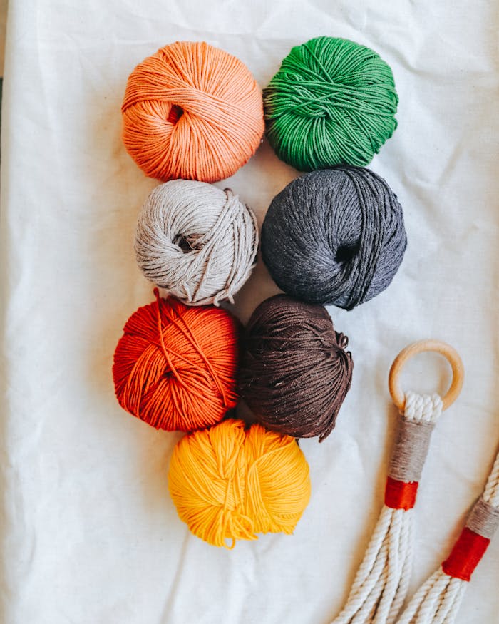 Vibrant yarn balls arranged on white fabric, perfect for crafting ideas.
