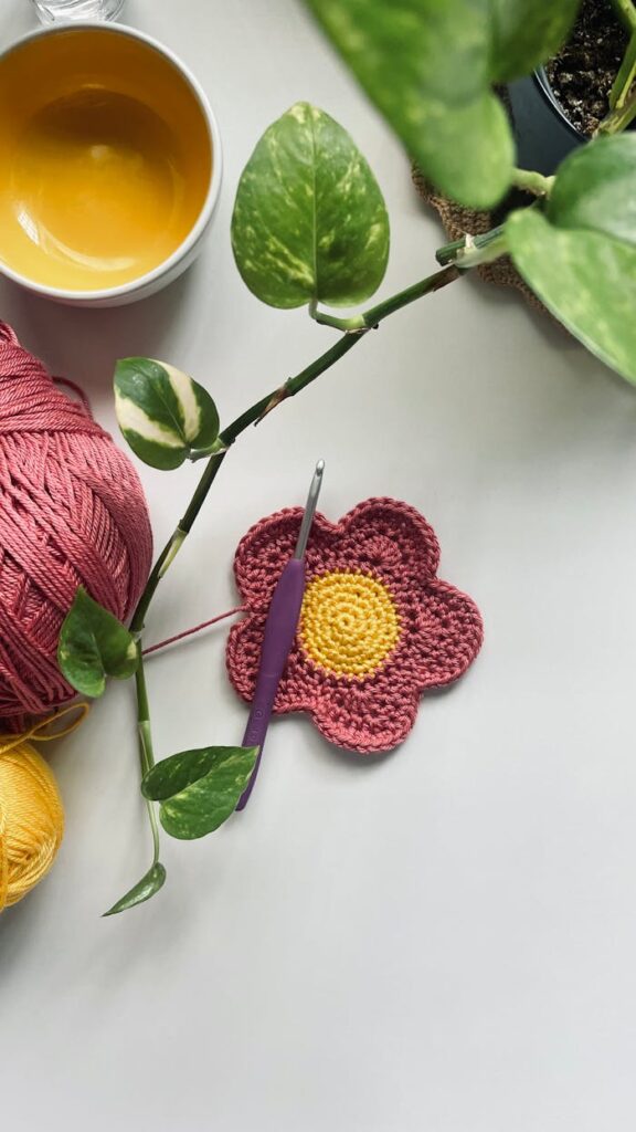 Handmade crochet flower and yarn with crochet hook on a white background.