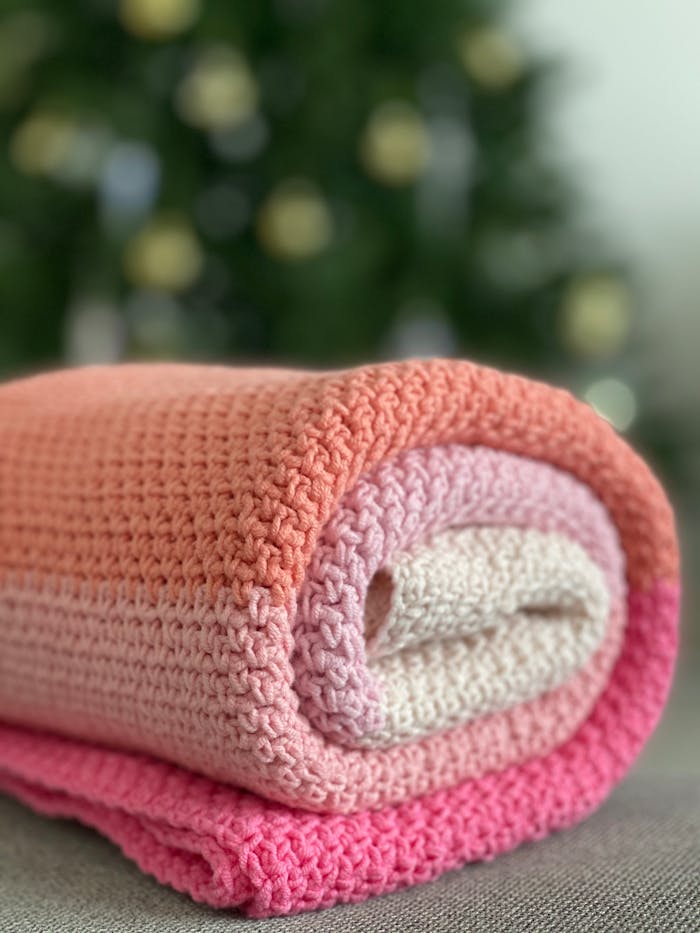 Close-up of a folded, handmade crocheted blanket with vibrant colors.