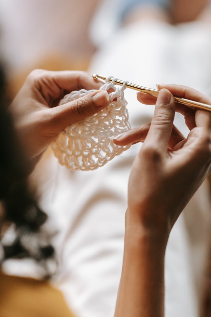 about-bg Intimate close-up of woman's hands knitting with white yarn, capturing the art of handmade craftsmanship.